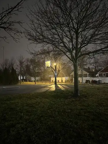 Quiet night, a single street light casts long, dramatic shadows.